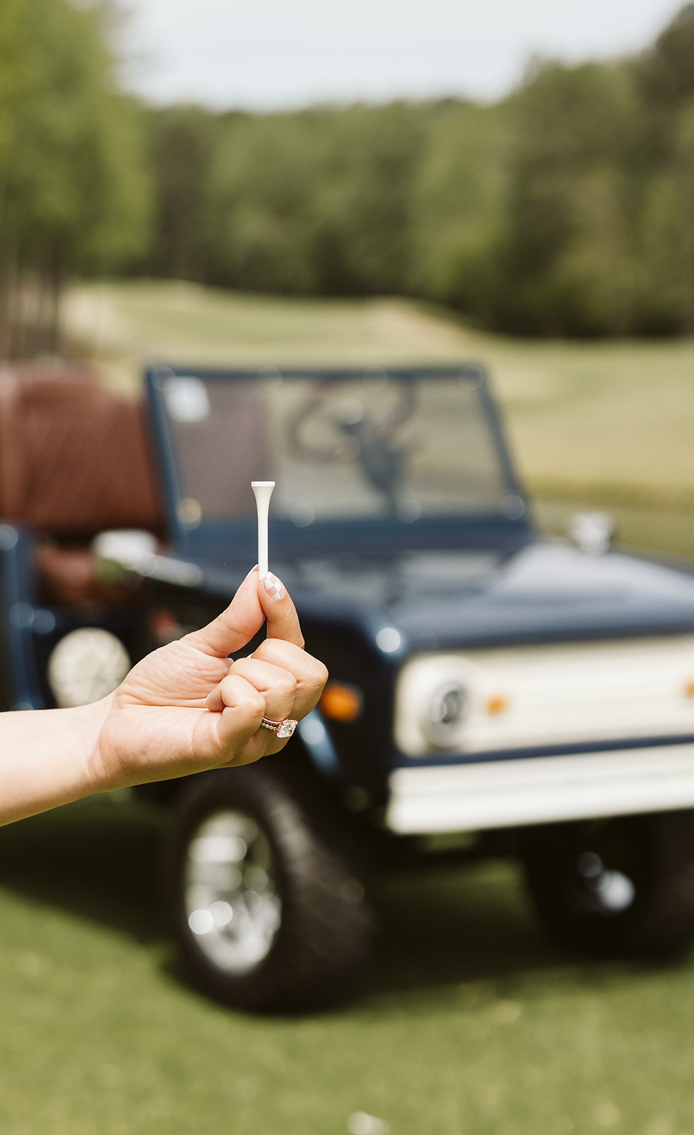 Golf tee in hand with Retro Ride on course behind