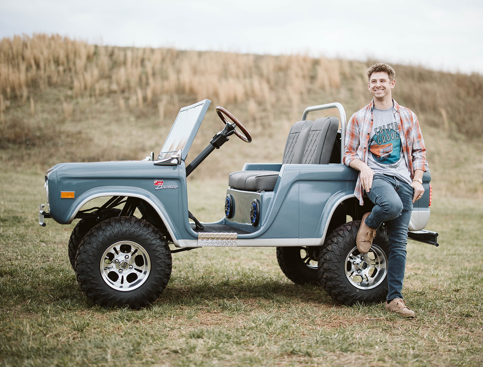 Founder leaning against Retro Ride in open field